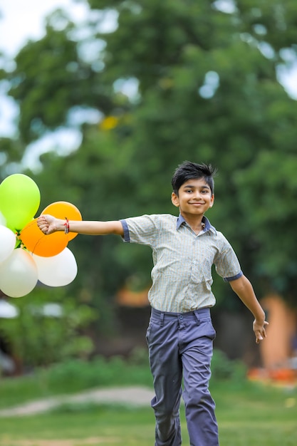 Lindo niño indio con globos de tres colores y celebrando el día de la independencia o la República de la India