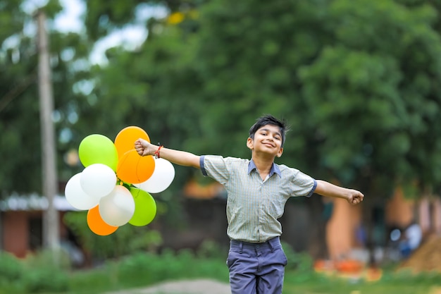 Lindo niño indio con globos de tres colores y celebrando el día de la independencia o la República de la India