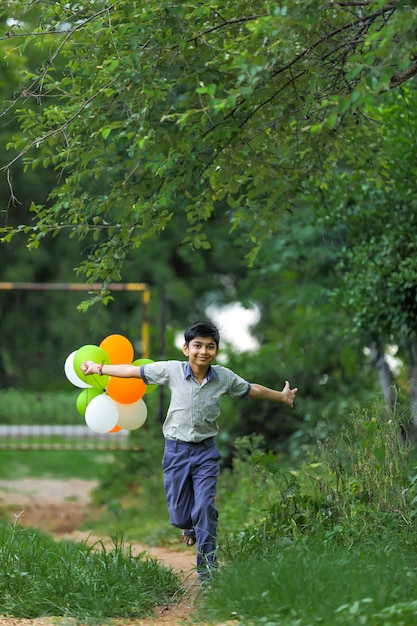 Lindo niño indio con globos de tres colores y celebrando el día de la independencia o la República de la India