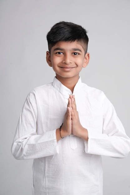 Lindo niño indio en namaste o pose de oración sobre fondo blanco.