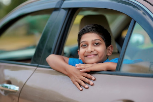 Lindo niño indio saludando desde la ventana del coche.