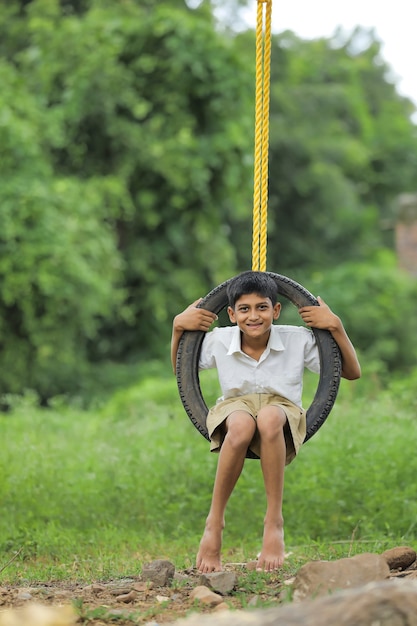 Lindo niño indio sentado en un columpio de neumáticos