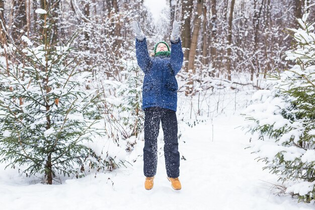 Lindo niño juega con nieve, diviértete, sonríe. Adolescente en el parque de invierno. Estilo de vida activo, actividad de invierno, juegos de invierno al aire libre, bolas de nieve.