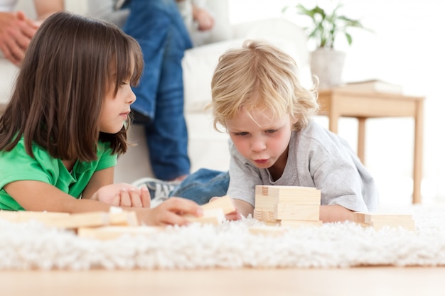 Lindo niño jugando al dominó con su hermana en el piso