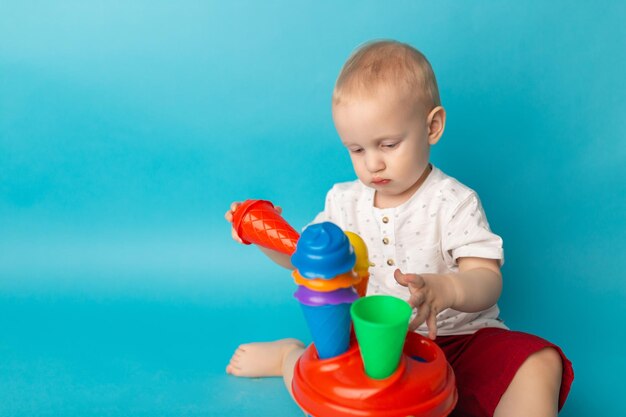 Lindo niño jugando con coloridos juguetes de plástico sentados en el suelo