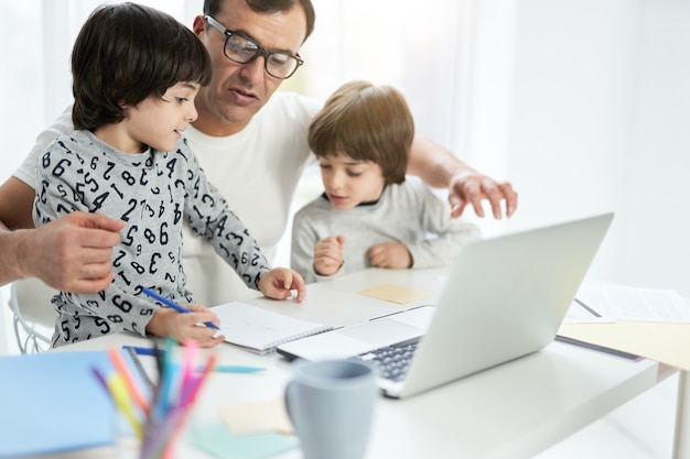 Lindo niño latino pasar tiempo con su padre y su hermano en casa empresario usando