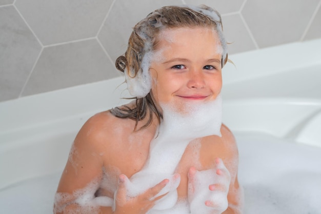 Lindo niño lavándose y bañándose en un baño con espuma cara de niño divertido bañado en el baño