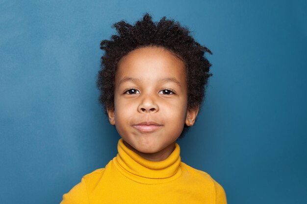 Un lindo niño negro en un retrato de fondo azul