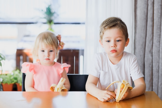 Lindo niño y niña comiendo plátano