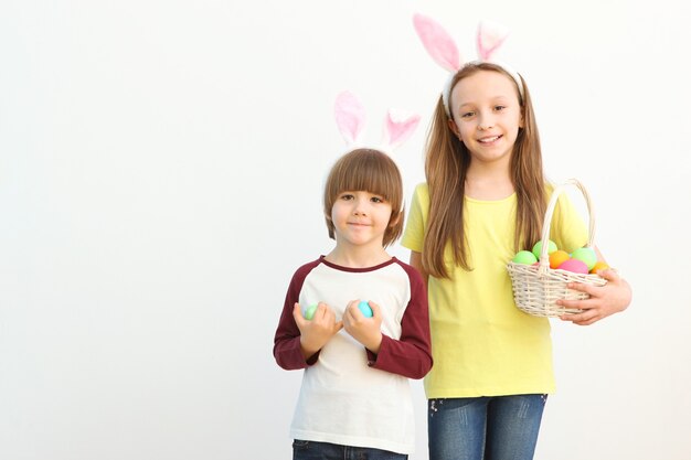 Lindo niño y niña en orejas de conejo y con una canasta de pascua