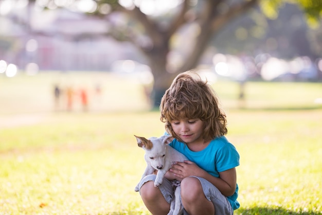 Lindo niño niño se siente encantado lleva cachorrito expresa emociones tiernas Cuidado infantil y amor a perrito pequeño Ternura amigos abrazos