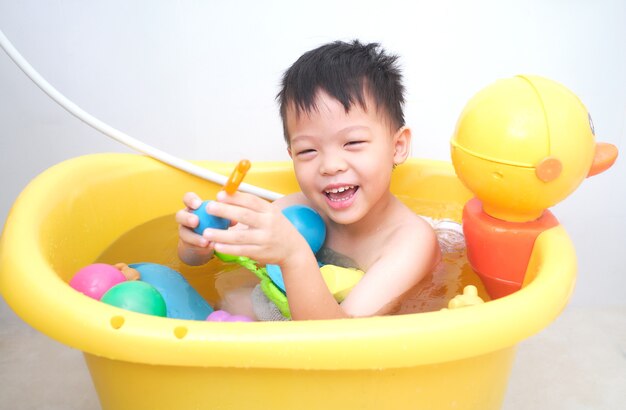 Lindo niño pequeño asiático tomando un baño solo solo en el baño en casa