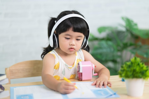 Lindo niño pequeño con auriculares blancos pintando con pinturas de colores Niña asiática usando madera color dibujo colorBaby artista actividad estilo de vida concepto