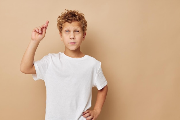 Lindo niño pequeño en una camiseta blanca posando un estilo de vida divertido inalterado