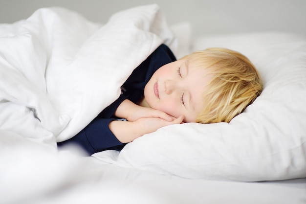 Lindo niño pequeño durmiendo Niño cansado tomando una siesta en la cama de los padres.