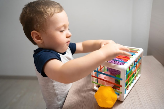 Un lindo niño pequeño está jugando un juego con bolas sensoriales de colores Actividades sensoriales y táctiles Juegos para niños de un año y medio Niño atento Enfoque en los ojos