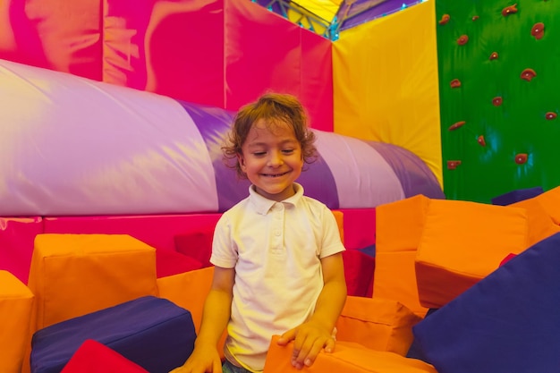 El lindo niño pequeño está parado entre cubos blandos