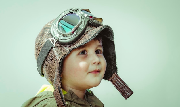 Lindo niño pequeño, jugando en casa jugando guerras y paz, niño divertido vestido con sombrero militar y gafas