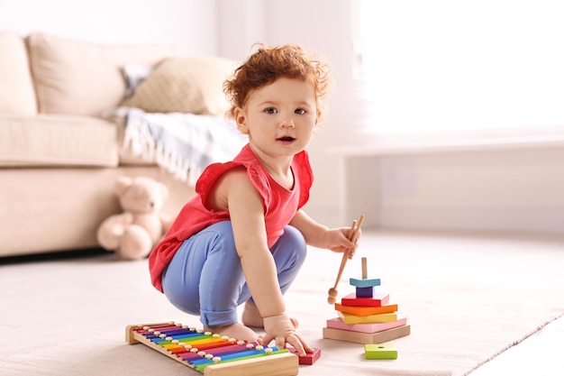 Lindo niño pequeño jugando con juguetes en el piso en casa