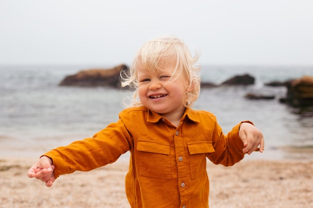 Lindo niño pequeño jugando en la playa en otoño