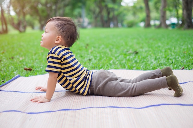 Lindo niño pequeño niño asiático niño practica yoga en pose de cobra y meditando al aire libre sobre la naturaleza en verano, concepto de estilo de vida saludable