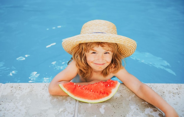 Lindo niño pequeño en la piscina comiendo sandía disfruta comiendo frutas tropicales niños de verano