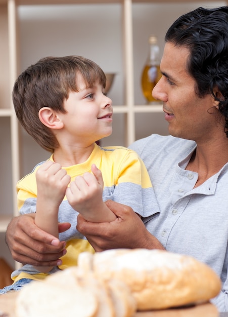 Lindo niño pequeño y su padre cortando pan