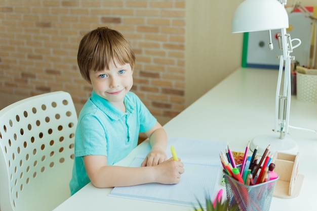 Lindo niño pintando con lápices de colores en casa, en la guardería o preescolar. Juegos creativos para niños que se quedan en casa