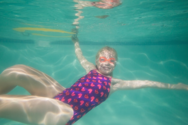 Lindo niño posando bajo el agua en la piscina