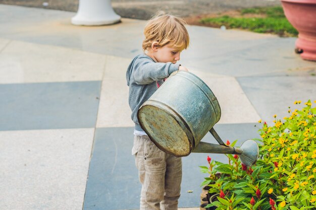 Lindo niño regando flores regadera