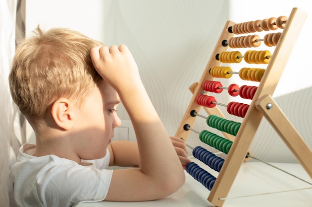 Foto un lindo niño rubio está comprometido con billetes de madera de colores juegos montessori educación conceptual