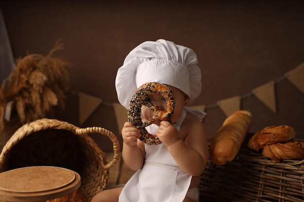 lindo niño rubio con un disfraz de chef mira en un agujero de bagel