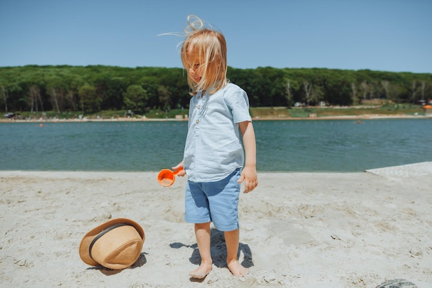 Lindo niño rubio feliz jugando con juguetes de playa en la playa de arena de la ciudad