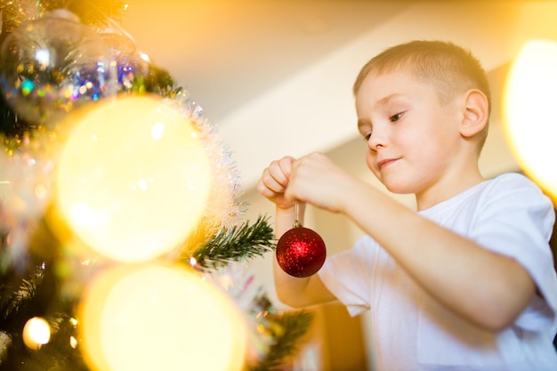 Lindo niño rubio sosteniendo su regalo de navidad en el tiempo de navidad autoaislamiento en cuarentena debido al coronavirus