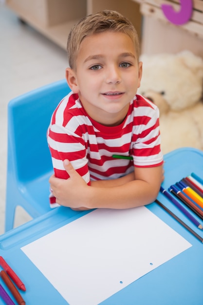 Lindo niño sentado en el escritorio