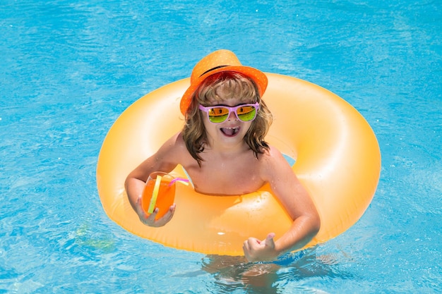 Lindo niño con sombrero y gafas de sol nadar en la piscina con fondo de agua azul felices vacaciones de verano niño h