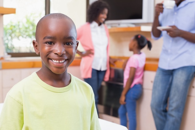 Lindo niño sonriendo a la cámara con la familia en el fondo