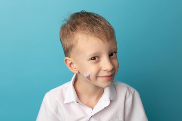 Lindo niño sonriente con una bandera rusa en la mejilla