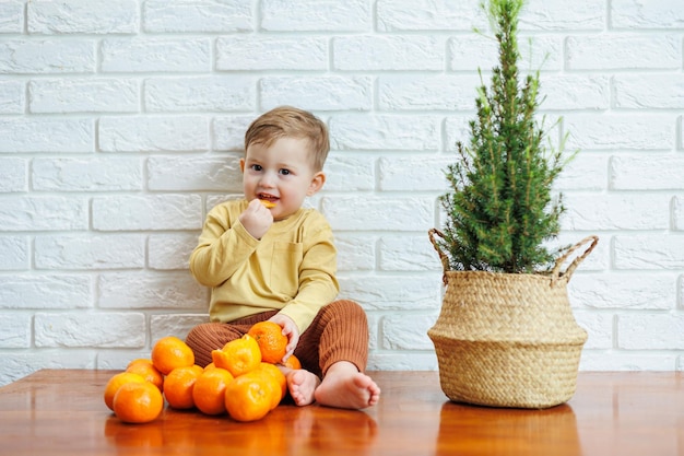 Lindo niño sonriente comiendo una mandarina fresca y jugosa