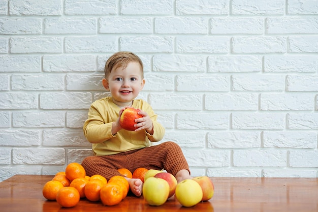 Lindo niño sonriente comiendo una manzana roja fresca y jugosa. Frutas saludables para niños pequeños