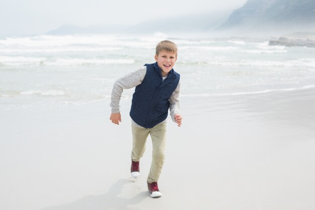 Lindo niño sonriente corriendo en la playa