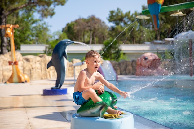 Un lindo niño sonriente se divierte en la piscina del parque acuático Actividades en la piscina Concepto descanso diversión