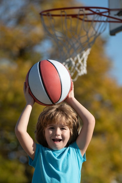 Lindo niño sonriente juega baloncesto niños activos disfrutando de juego al aire libre con baloncesto