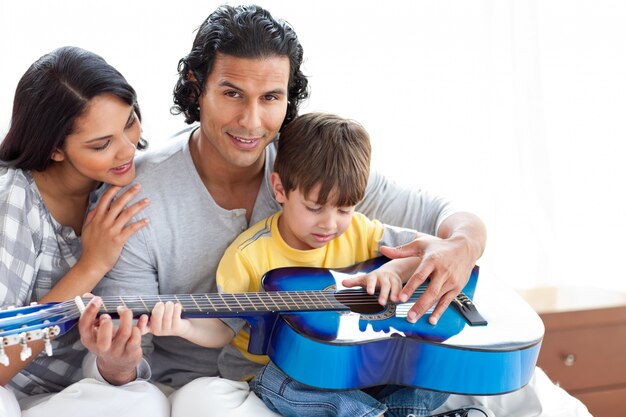 Lindo niño tocando la guitarra con sus padres