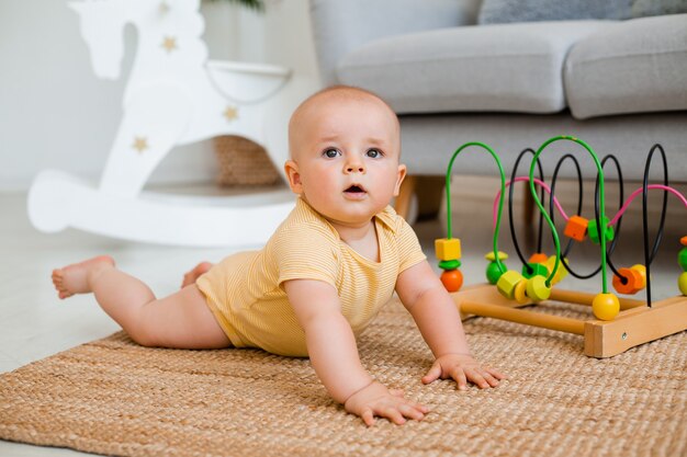 Lindo niño en traje amarillo se sienta en casa en el suelo jugando en un juguete en desarrollo. concepto de desarrollo infantil