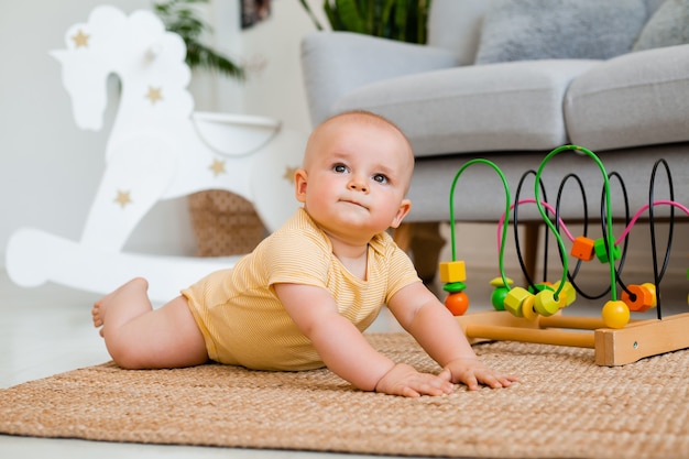 Lindo niño en traje amarillo se sienta en casa en el suelo jugando en un juguete en desarrollo. concepto de desarrollo infantil