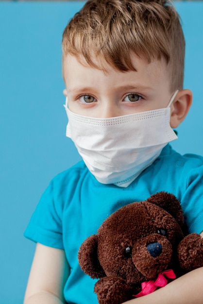 Lindo niño usando nebulizador sobre fondo azul Concepto de alergia