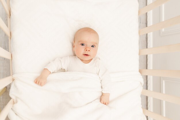 Lindo pequeño bebé sentado en la cama