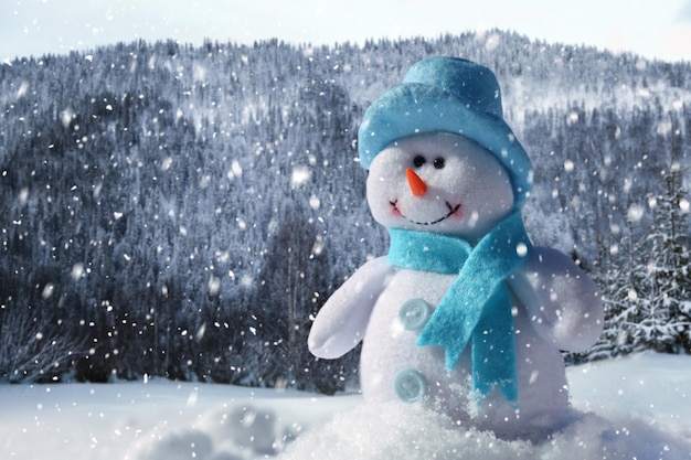 Lindo pequeño muñeco de nieve decorativo al aire libre en un día soleado espacio para texto