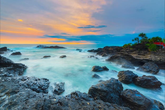 lindo pôr do sol com fileiras de pedras na praia de Menganti, na Indonésia